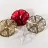 Three round, Aromaglow floating candles in metallic gold, silver, and red, arranged on a white background.